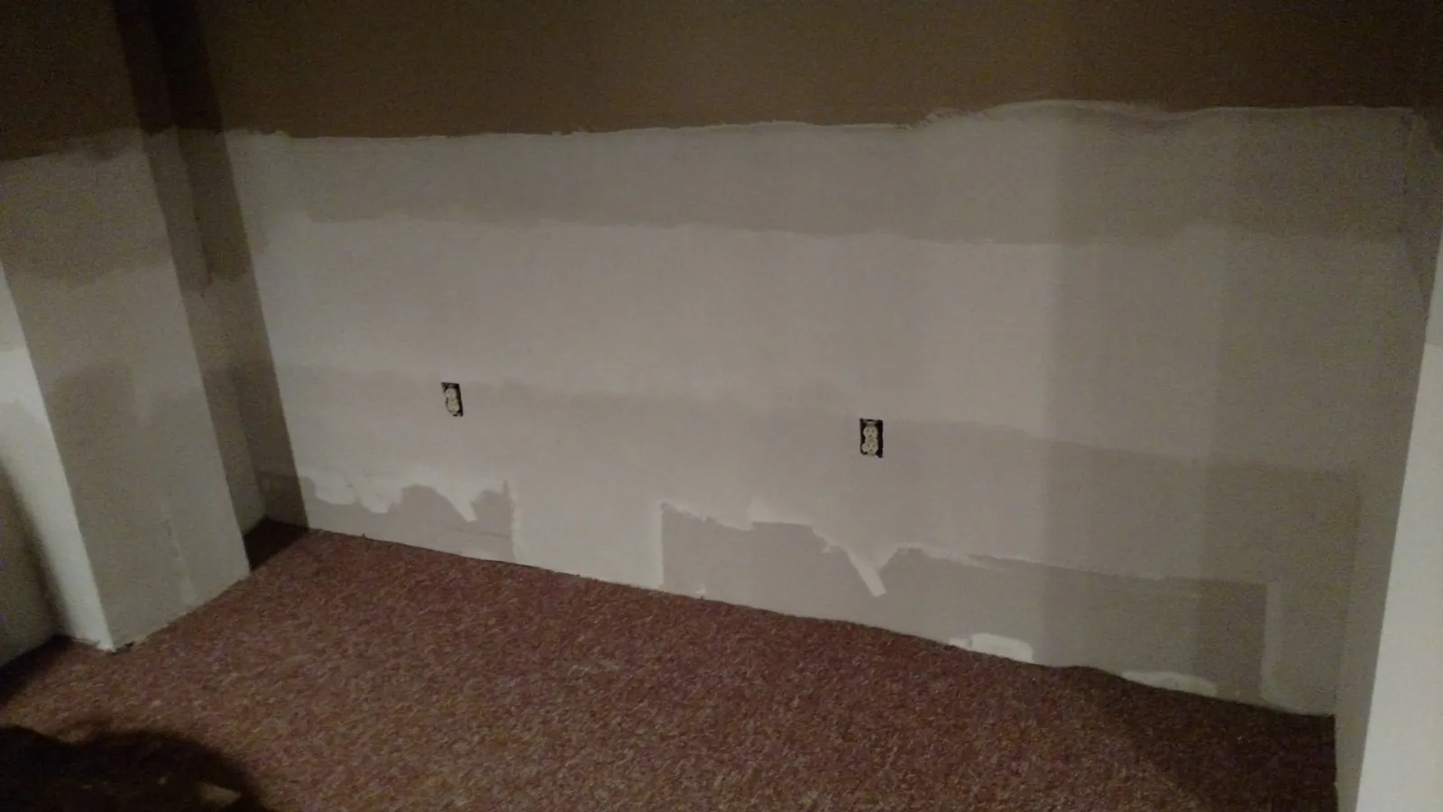 Basement wall with drywall patches along the bottom