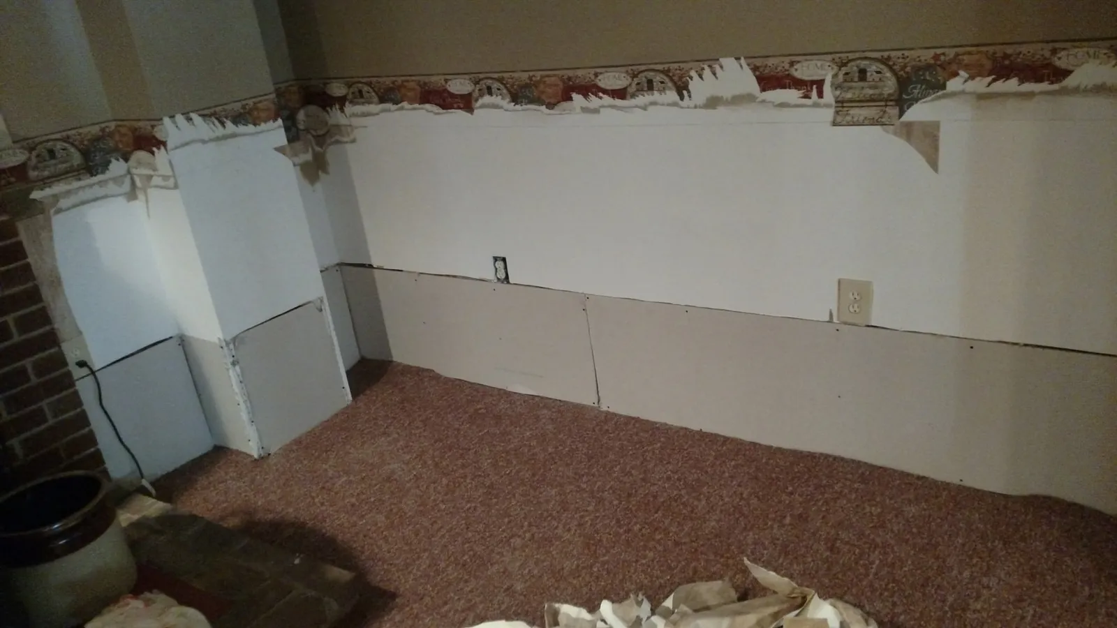 Basement wall with damaged lower drywall cut out and patched